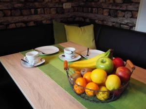 eine Schale Obst auf einem Tisch mit Tassen und Tellern in der Unterkunft Ferienwohnung an der Waldmühle in Reulbach