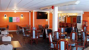jadalnia ze stołami i krzesłami oraz telewizorem w obiekcie Anchor Inn Hotel and Suites w mieście Twillingate