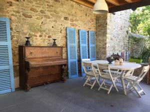 a dining room with a table and a piano at Gîte La Glycinière in Pont-Croix