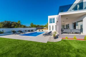 a backyard with a swimming pool and a house at Villa Pollux - Adriatic Luxury Villas in Vrsi