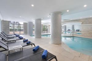 a pool in a hotel with blue lounge chairs at Maritim Antonine Hotel & Spa in Mellieħa