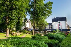 a park with trees and bushes and a white building at Hotel Schaepkens van St Fijt in Valkenburg