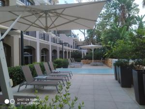 a group of chairs under an umbrella next to a pool at Maritim Antonine Hotel & Spa in Mellieħa