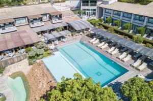 una vista aérea de una piscina con sillas y un edificio en Hôtel Le Roi Théodore & Spa en Porto Vecchio