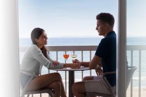 a man and woman sitting at a table with glasses of wine at Hotel Maritim in Roses