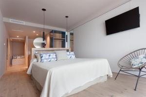 a bedroom with a white bed and a chair at Hotel Maritim in Roses