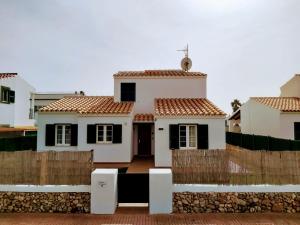 una casa blanca con una valla delante en Grupoandria Villa TIERRASOL, Ciutadella, en Cala en Blanes