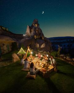 a group of people sitting around a table at night at Argos in Cappadocia in Uçhisar