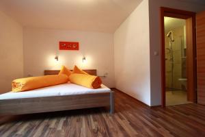 1 dormitorio con cama con almohadas de color naranja y ducha en Apart Arve, en Sankt Leonhard im Pitztal