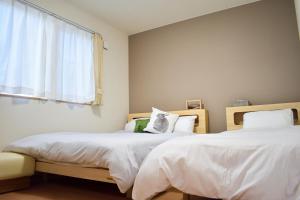 2 nebeneinander sitzende Betten in einem Schlafzimmer in der Unterkunft TKD HOUSE FURANO in Furano
