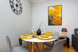 comedor con mesa con sillas y reloj en Apartment Warsaw Kredytowa by Renters en Varsovia