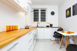 une cuisine avec des placards blancs et un comptoir en bois dans l'établissement Apartment Warsaw Kredytowa by Renters, à Varsovie