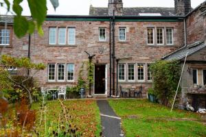 an old brick house with a pathway leading to the front door at Beech House in Greystoke