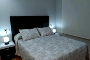 a bedroom with a large bed with two night stands and two lamps at DISFRUTE DE SUS VACACIONES CON WIFI EN EL PUERTO DE CARIÑo in Cariño