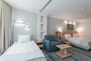 a hotel room with two beds and a blue chair at Hotel Neptun Beach in Sunny Beach
