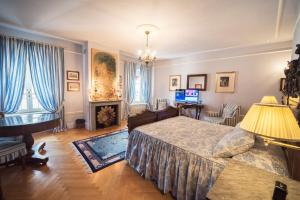 
a bedroom with a bed, chair, desk and television at Palazzo Dalla Rosa Prati in Parma
