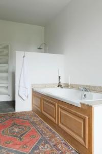 een badkamer met een grote witte wastafel en een tapijt bij Château de Martigny 