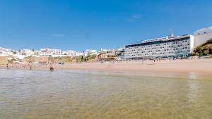 
a beach scene with people walking on the beach at Hotel Sol e Mar Albufeira in Albufeira
