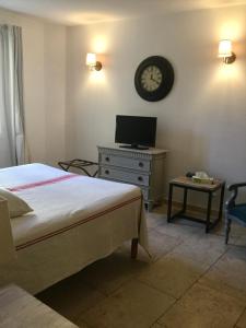 a bedroom with a bed and a clock on the wall at Un Coin De Luberon in L'Isle-sur-la-Sorgue