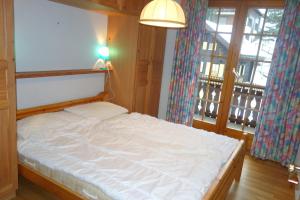1 dormitorio con 1 cama blanca con lámpara y ventanas en Royal 141 SKI LIFT & TERRACE apartment 8 pers by Alpvision Résidences, en Veysonnaz