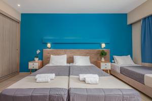 2 camas en un dormitorio con una pared azul en Poseidon Beach Hotel, en Laganas