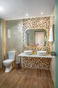 ein Badezimmer mit zwei Waschbecken, einem WC und einem Spiegel in der Unterkunft Poseidon Beach Hotel in Laganas