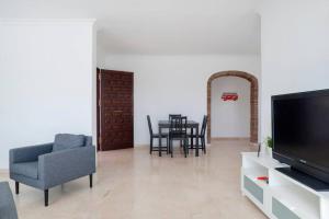 a living room with a tv and a table and chairs at 049 - Modern & Spacious Holiday Villa With Private Pool in Fuengirola
