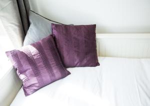 two purple pillows sitting on top of a bed at The Tushmore in Crawley