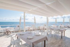a restaurant with tables and chairs on the beach at Hotel Cavalluccio Marino in Santa Marinella
