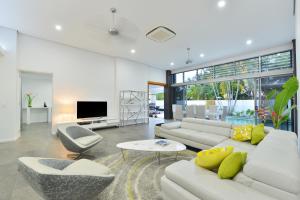 a living room with white furniture and a tv at #2 Andrews – Port Douglas in Port Douglas