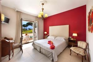 a bedroom with a white bed and a red wall at Hotel Alpha in Sant'Agnello