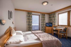 a hotel room with a bed and a desk and window at Landhaus Schneeberger in Mayrhofen
