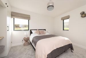 a white bedroom with a large bed and two windows at Bramble in Ansty