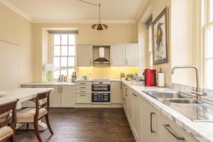 a kitchen with white cabinets and a sink and a table at Park House in Dorchester