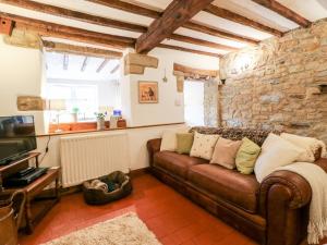a living room with a brown leather couch and a tv at Hallbrook Cottage in Matlock