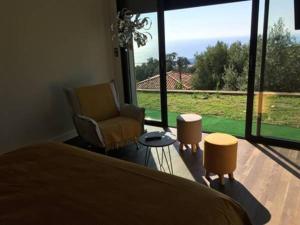 a bedroom with a bed and a chair and a large window at Maison d'hôtes Bastia in Bastia