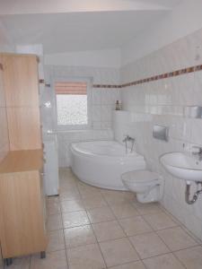 a bathroom with a tub and a toilet and a sink at App. Weisses Haus in Hohen Neuendorf