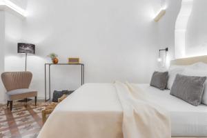 a white bedroom with a bed and a chair at Palais Gentile Matino in Matino