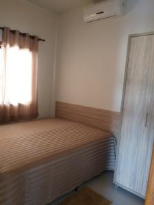um pequeno quarto com uma cama e uma janela em Casa de praia no Condomínio Guaratiba, Prado-BA em Prado
