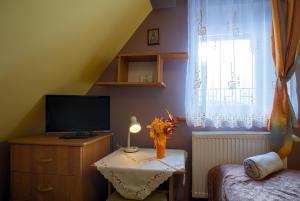 um pequeno quarto com televisão e uma mesa com flores em Zajazd Czorsztyński em Maniowy