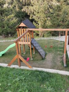 un parque infantil de madera con un tobogán y una escalera en Біла хата, en Iltsi