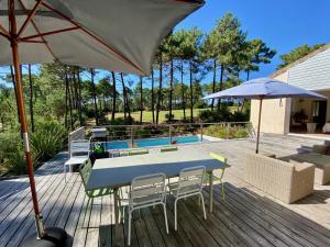 a patio with a table and chairs and an umbrella at Villa les Mimosas with pool and fantastic views in Lacanau