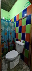 a bathroom with a toilet and a colorful tiled wall at Hostel Tortuguero 7BackPackers in Tortuguero
