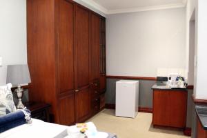 Zimmer mit einem großen Holzschrank und einem Kühlschrank in der Unterkunft Prinshof Manor Guesthouse in Pretoria