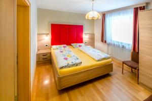 sypialnia z dużym łóżkiem z czerwonym zagłówkiem w obiekcie Apartments Diamant w mieście Ortisei