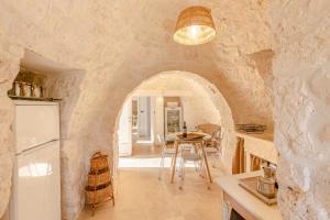 een keuken en eetkamer met een stenen muur bij Il trullo della Quercia in San Michele Salentino