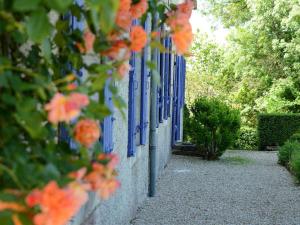 un mur blanc avec des fenêtres bleues et des fleurs orange dans l'établissement Chambres d'Hôtes La Sauvageonne, à Saint-Palais