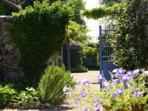 un jardin avec une porte bleue et des fleurs violettes dans l'établissement Chambres d'Hôtes La Sauvageonne, à Saint-Palais