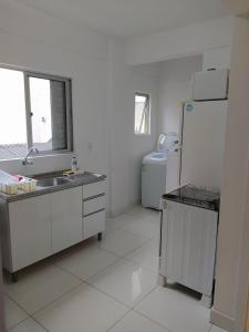Una cocina blanca con fregadero y refrigerador. en Apartamento no centro - 2, en Balneário Camboriú