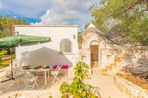 un patio con una mesa y una sombrilla verde en Il trullo della Quercia, en San Michele Salentino